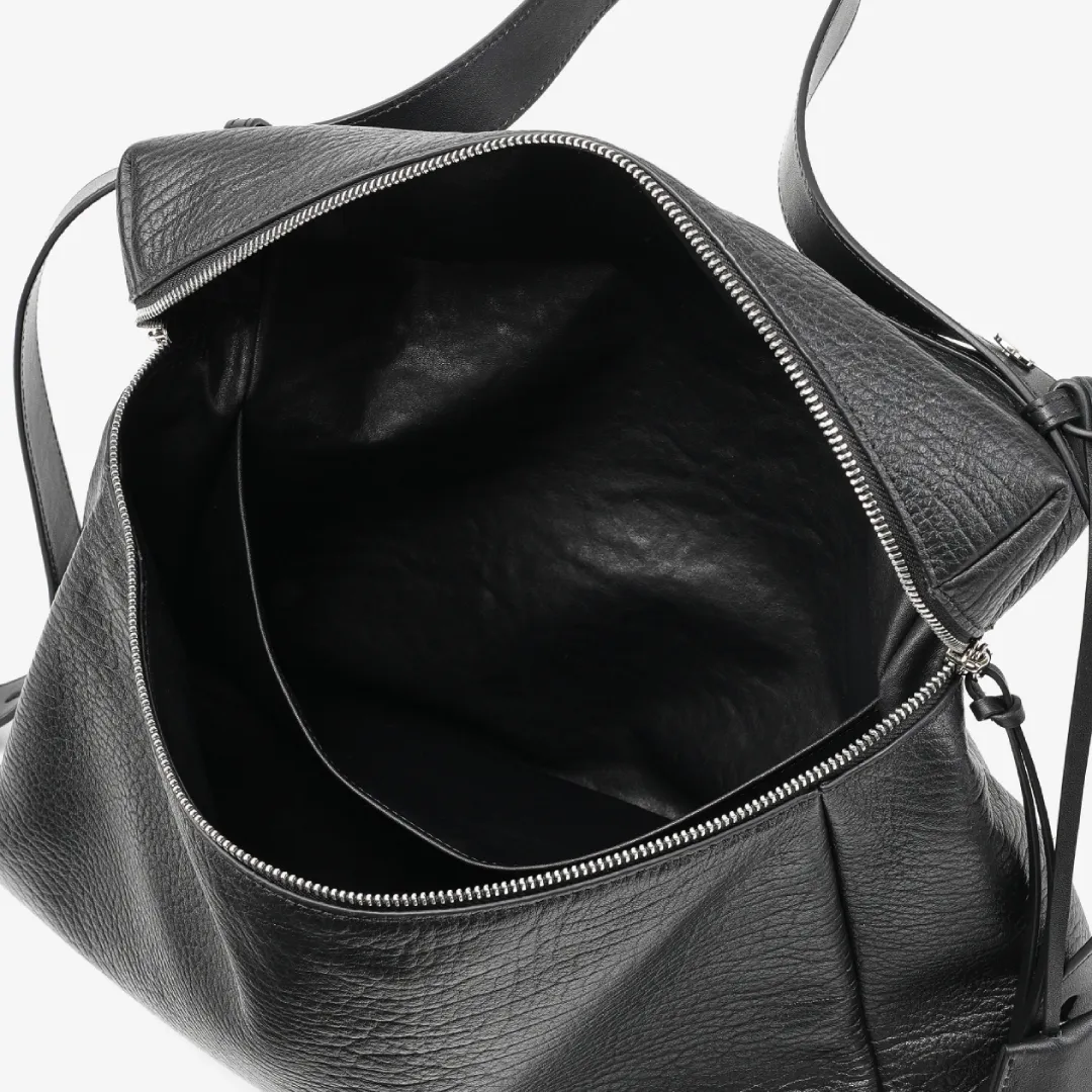 The main compartment features a wide-opening design with built-in organizational pockets. Its generous capacity is perfectly suited for both short getaways and professional settings, with ample space to accommodate a 15-inch laptop. This bag seamlessly blends high-level practicality with a design aesthetic that fuses timeless elegance with a bold, free-spirited character.